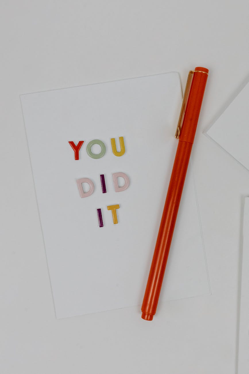 Words on a page read, "You did it." A red pen lies next to the words.